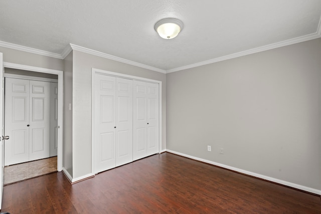 unfurnished bedroom with ornamental molding, dark wood-style floors, a closet, and baseboards