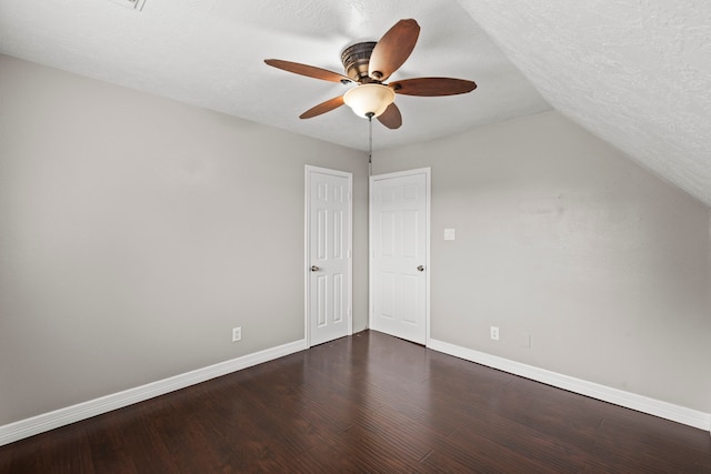 interior space with lofted ceiling, ceiling fan, dark wood finished floors, and baseboards