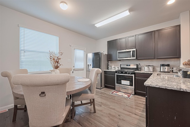 4807 Purple Wisteria Ln, Spring, TX 77373 - kitchen featuring appliances with stainless steel finishes, a sink, light wood-style floors, and light stone countertops