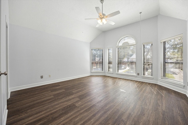 empty room with baseboards, ceiling fan, dark wood-type flooring, and vaulted ceiling