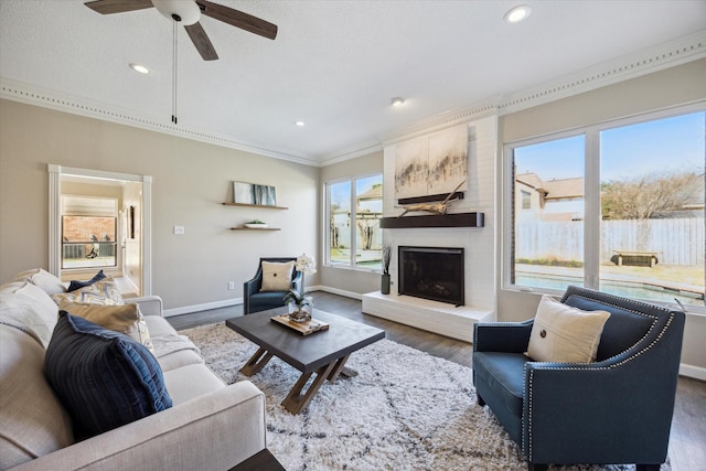 living area featuring ornamental molding, ceiling fan, dark wood-type flooring, and plenty of natural light