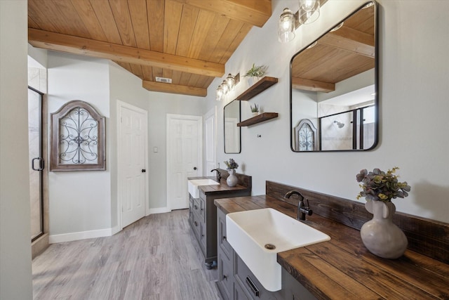 bathroom with a stall shower, a sink, beamed ceiling, and wood ceiling