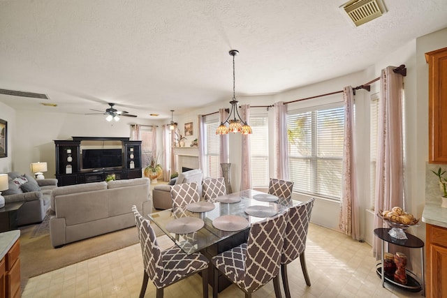 13823 Eldridge Garden Cir, Houston, TX 77083 - dining area featuring a textured ceiling, visible vents, light floors, and ceiling fan with notable chandelier