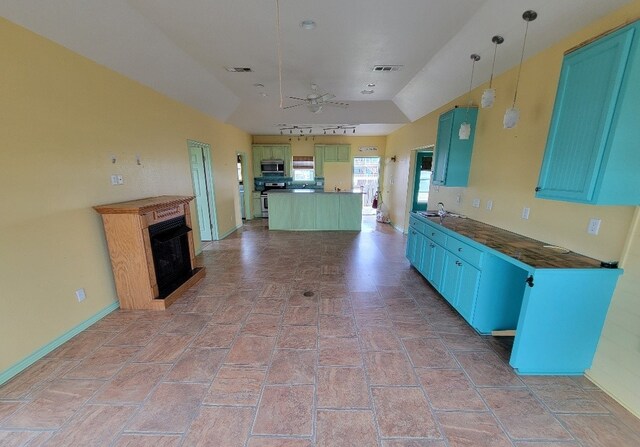 kitchen featuring stainless steel appliances, ceiling fan, a kitchen island, dark countertops, and lofted ceiling