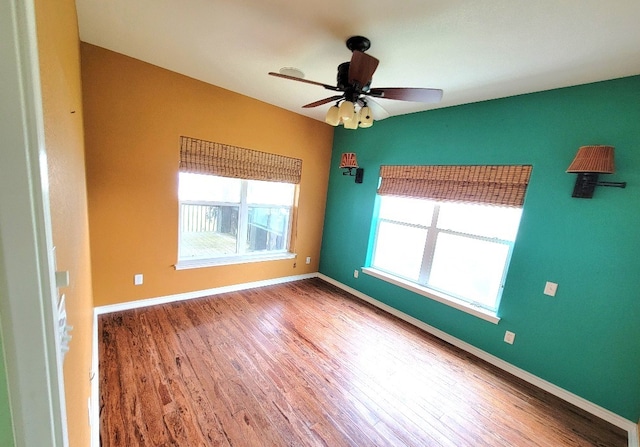 empty room with wood finished floors, a ceiling fan, and baseboards