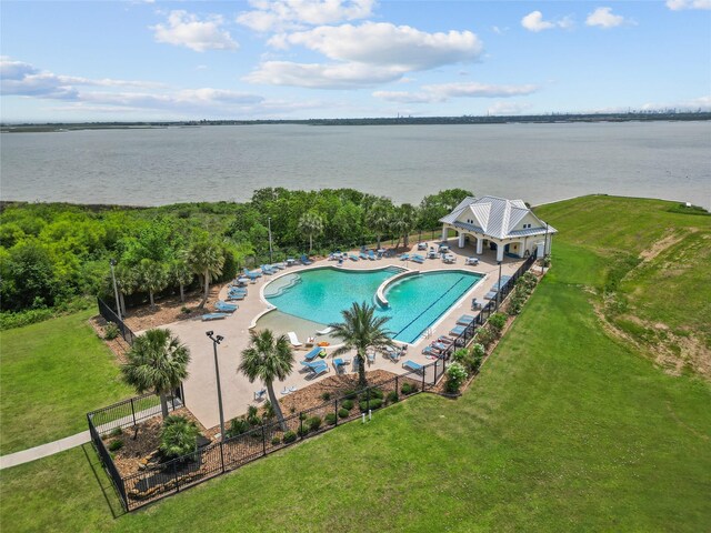 pool featuring a patio, a water view, fence, and a yard