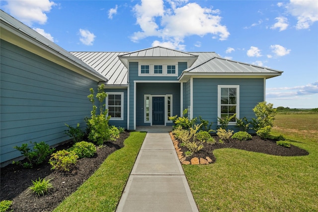 entrance to property featuring metal roof, a yard, and a standing seam roof