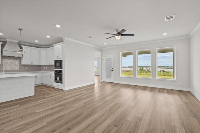 unfurnished living room featuring crown molding, baseboards, a ceiling fan, and visible vents