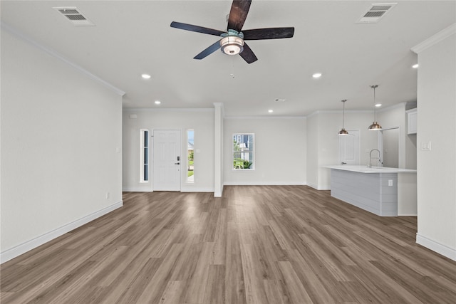 unfurnished living room with visible vents, ornamental molding, and light wood-type flooring