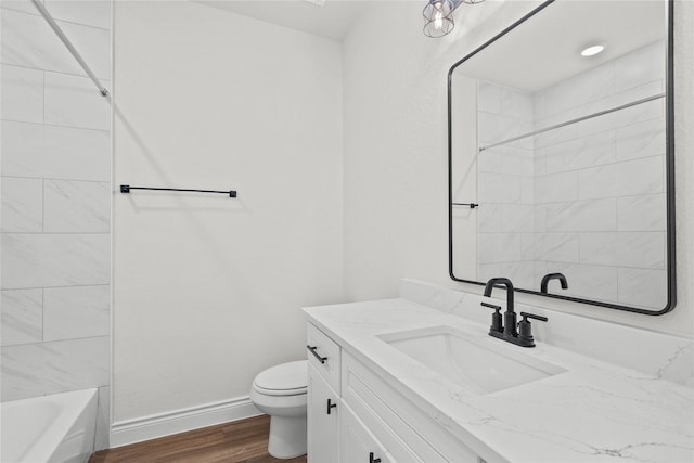 bathroom with toilet, baseboards, wood finished floors, and vanity