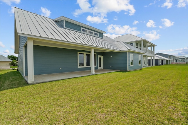 rear view of house featuring a standing seam roof, a patio, a yard, and metal roof