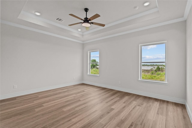 empty room featuring ceiling fan, visible vents, a raised ceiling, baseboards, and light wood-style floors