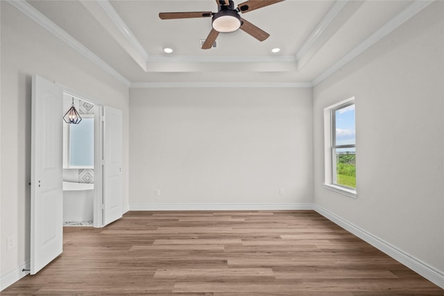 unfurnished bedroom with baseboards, light wood-style floors, ornamental molding, a tray ceiling, and recessed lighting
