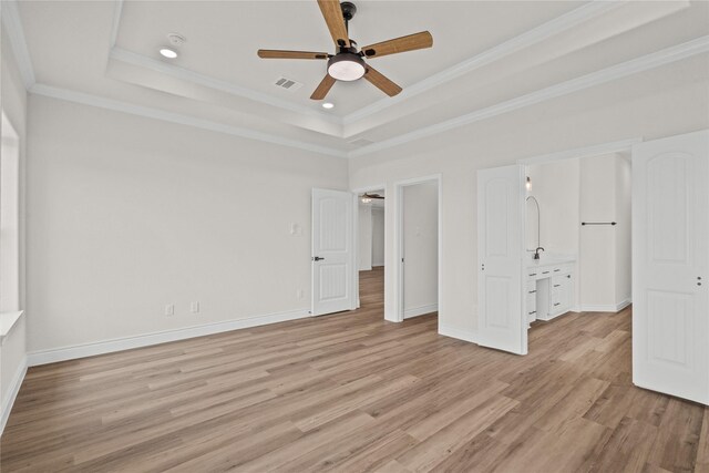 unfurnished bedroom featuring crown molding, a tray ceiling, visible vents, and light wood-style flooring