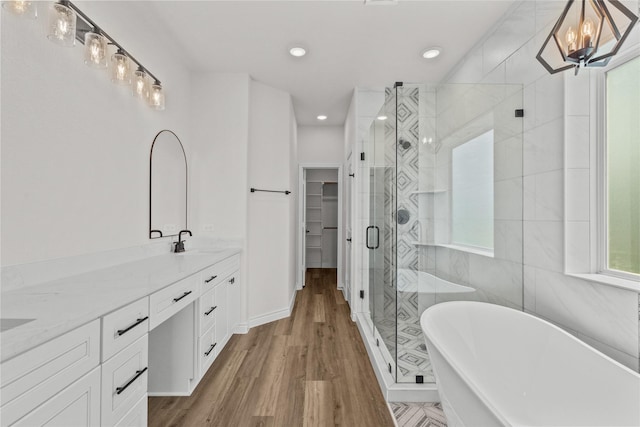 full bathroom featuring a sink, double vanity, recessed lighting, a shower stall, and a soaking tub