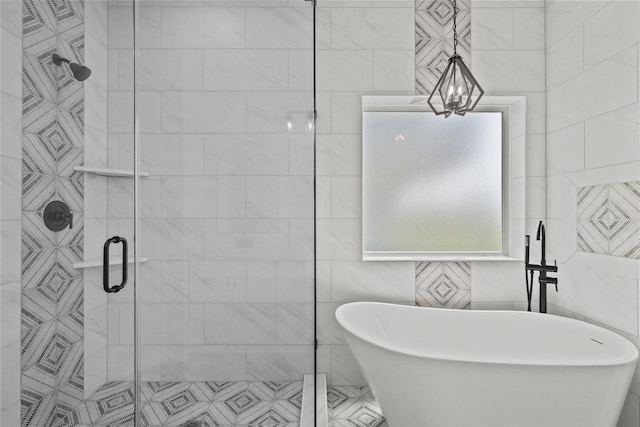 bathroom featuring tile walls, a freestanding tub, a chandelier, and a stall shower