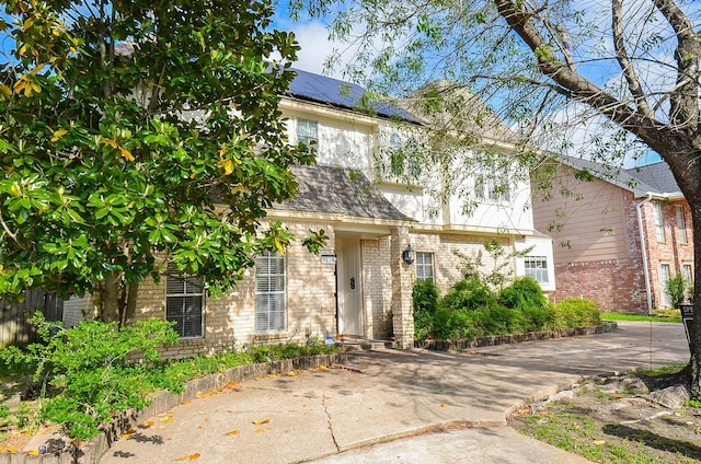 view of front of home featuring brick siding and solar panels