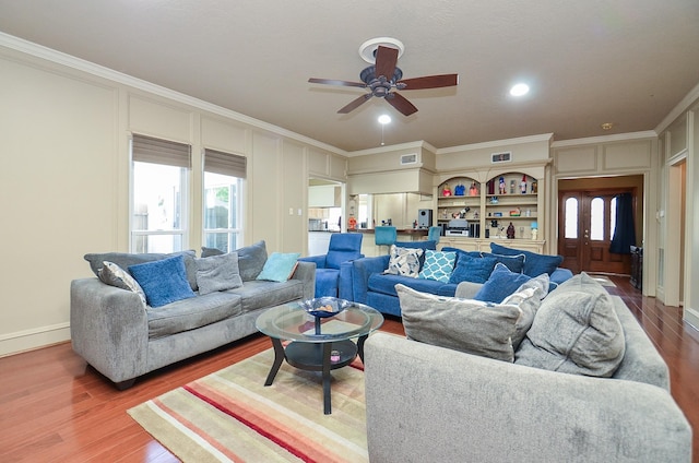 living room featuring crown molding, a ceiling fan, wood finished floors, and visible vents