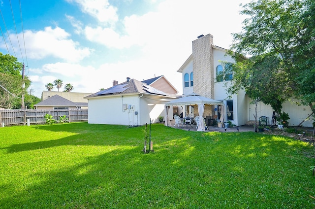 back of property with a lawn, a patio area, a gazebo, a fenced backyard, and stucco siding