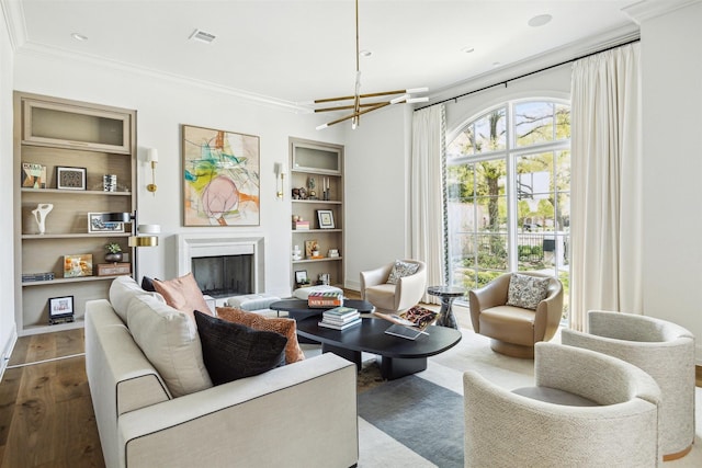 2023 Drexel Dr, Houston, TX 77027 - living room with crown molding, a fireplace, wood finished floors, a notable chandelier, and built in shelves