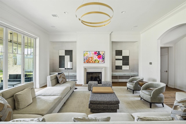 2023 Drexel Dr, Houston, TX 77027 - living area featuring a glass covered fireplace, crown molding, visible vents, arched walkways, and wood finished floors