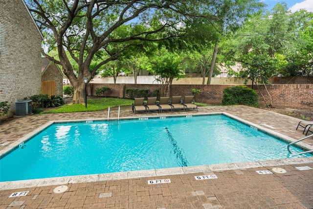 community pool featuring a patio, a fenced backyard, and central air condition unit