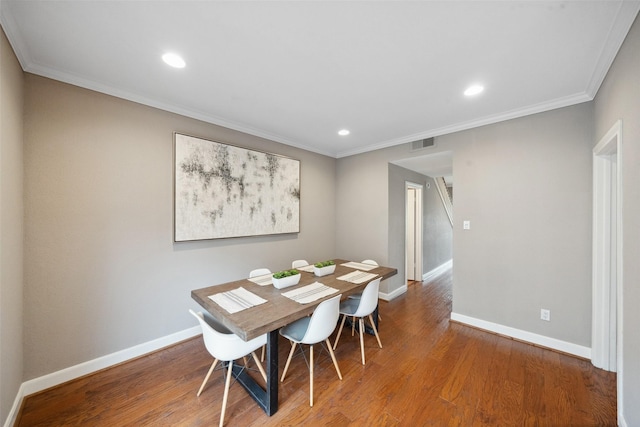 dining room with crown molding, baseboards, visible vents, and wood finished floors