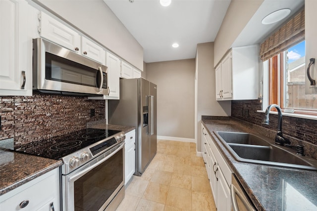 kitchen featuring decorative backsplash, appliances with stainless steel finishes, a sink, baseboards, and white cabinetry