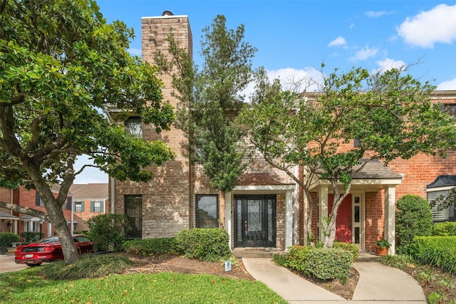 view of front of property featuring a chimney and brick siding