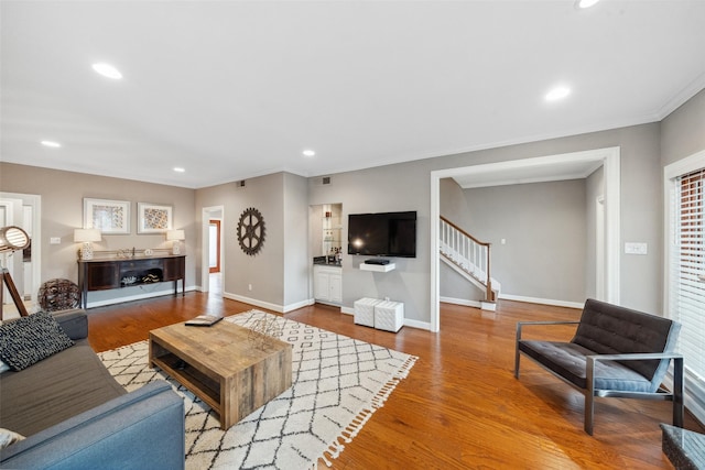 living area with visible vents, crown molding, stairs, wood finished floors, and recessed lighting
