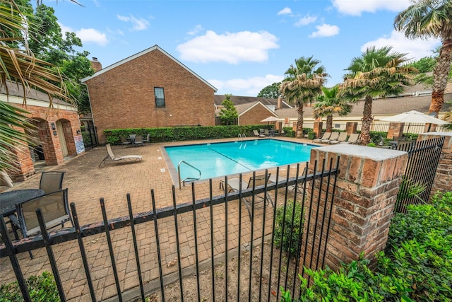 community pool with fence and a patio area