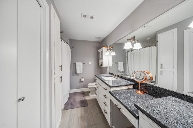 bathroom with visible vents, vanity, toilet, baseboards, and a shower with shower curtain