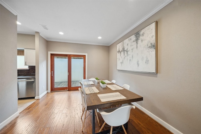 dining area featuring light wood-style floors, ornamental molding, and baseboards