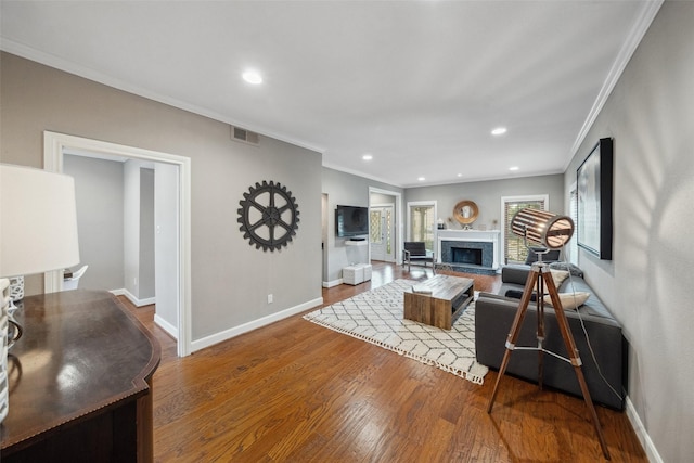 living area featuring visible vents, crown molding, wood finished floors, baseboards, and recessed lighting