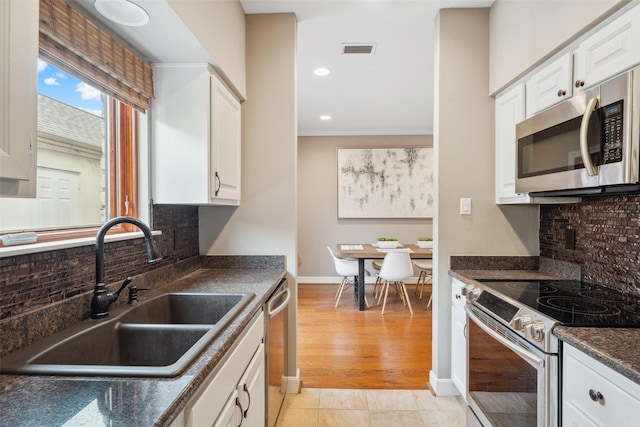 kitchen featuring visible vents, dark countertops, a sink, white cabinets, and stainless steel appliances