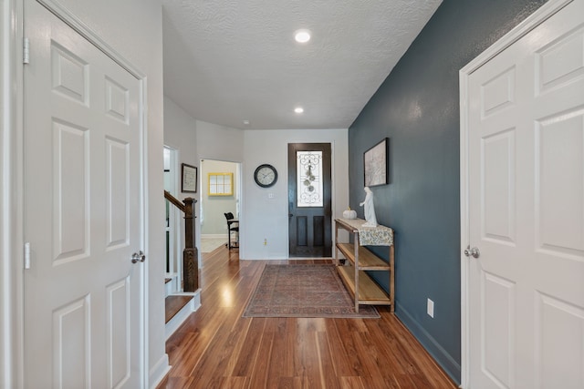 entryway with dark wood finished floors, baseboards, stairs, and a textured ceiling