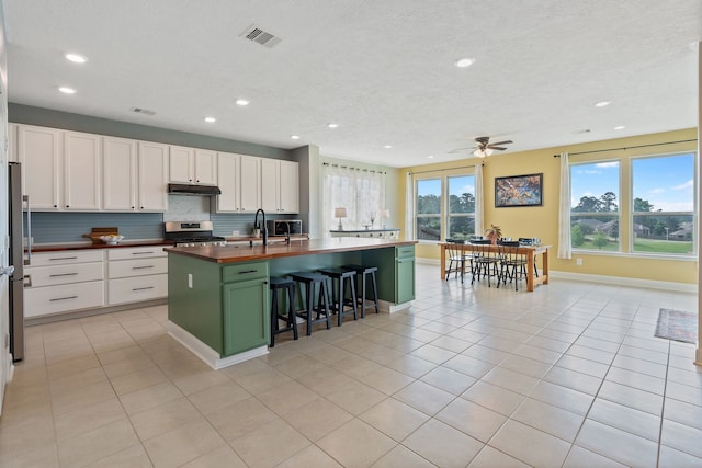 kitchen with appliances with stainless steel finishes, green cabinets, under cabinet range hood, and recessed lighting