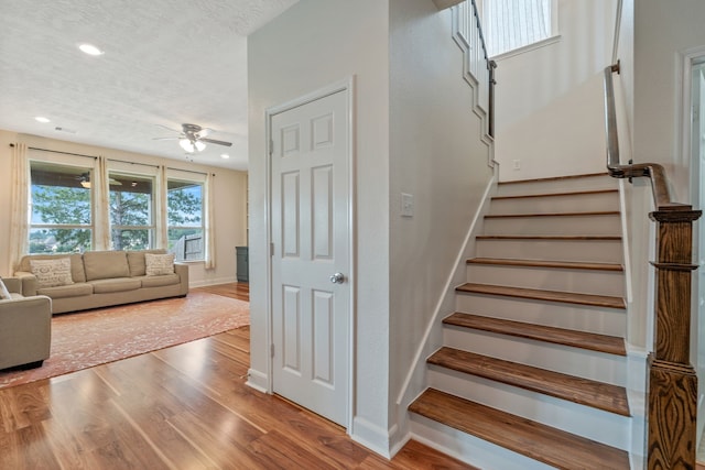 staircase with baseboards, ceiling fan, a textured ceiling, and wood finished floors