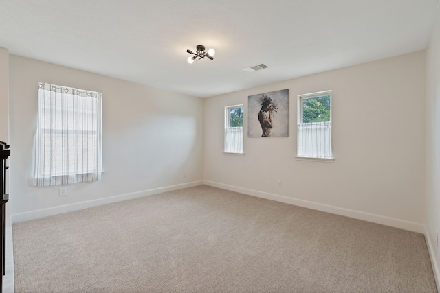 carpeted empty room featuring baseboards and visible vents