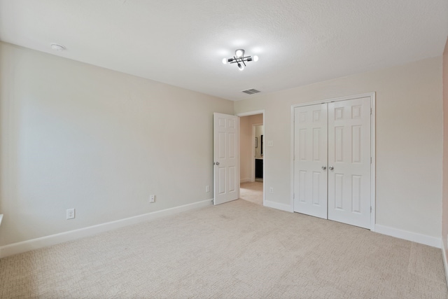 unfurnished bedroom featuring light colored carpet, baseboards, visible vents, and a closet