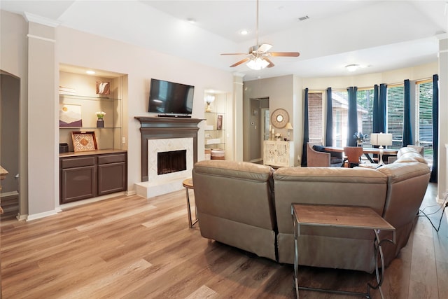 living room featuring light wood-style floors, a ceiling fan, visible vents, ornate columns, and a high end fireplace