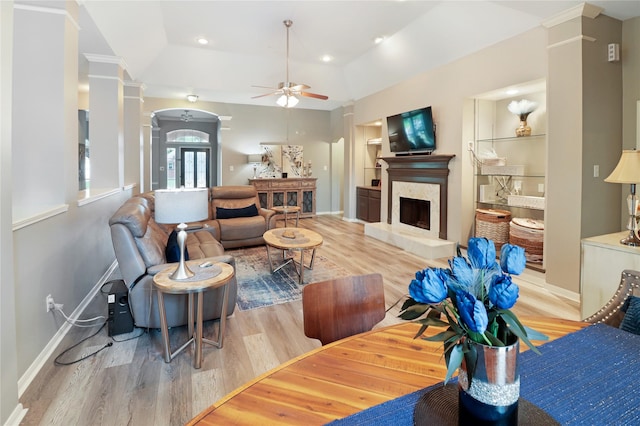living area with baseboards, ornate columns, a ceiling fan, and light wood-style floors