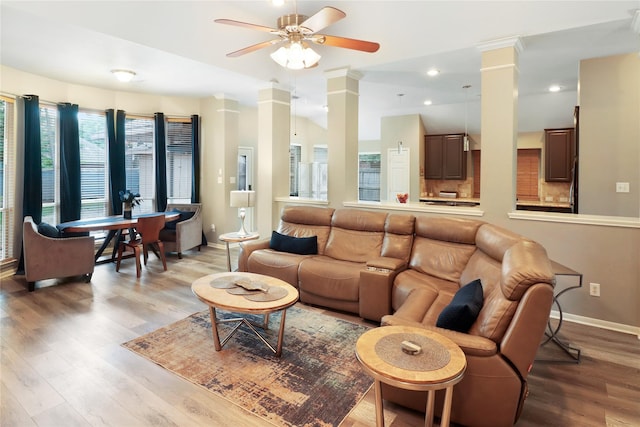 living room featuring a ceiling fan, light wood-style flooring, baseboards, and decorative columns