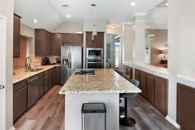 kitchen featuring light wood-style flooring, a sink, appliances with stainless steel finishes, visible vents, and a center island