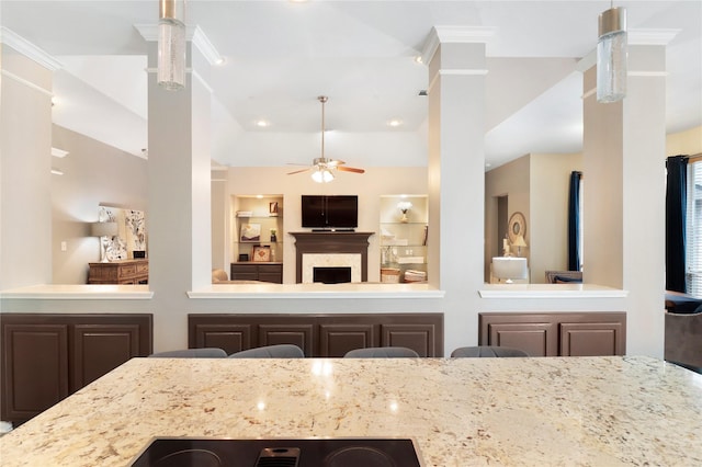 kitchen featuring light stone countertops, a fireplace, built in features, a ceiling fan, and lofted ceiling