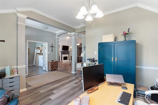 home office with a notable chandelier, ornate columns, ornamental molding, arched walkways, and wood finished floors
