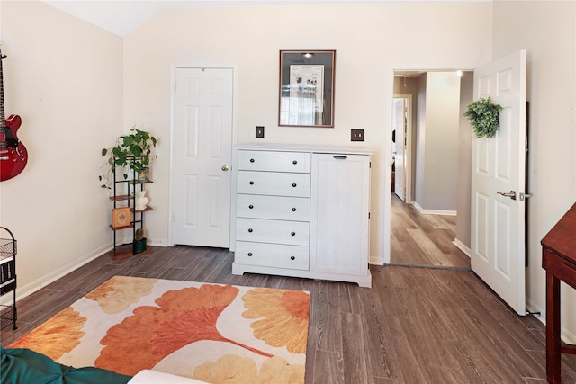 bedroom featuring dark wood-style flooring, vaulted ceiling, and baseboards