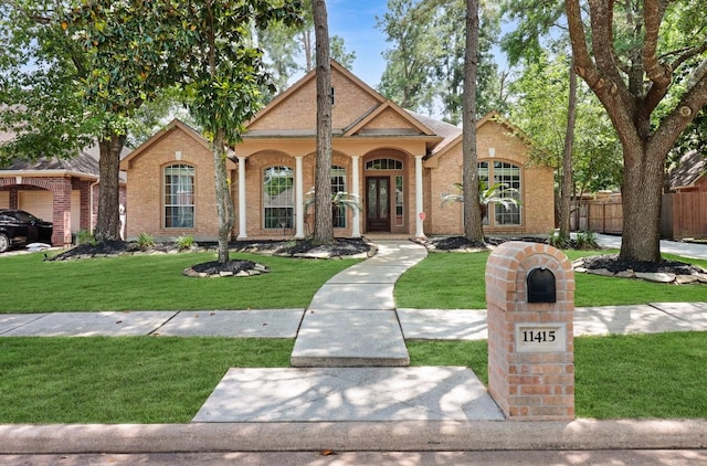 mediterranean / spanish house featuring fence, brick siding, and a front lawn
