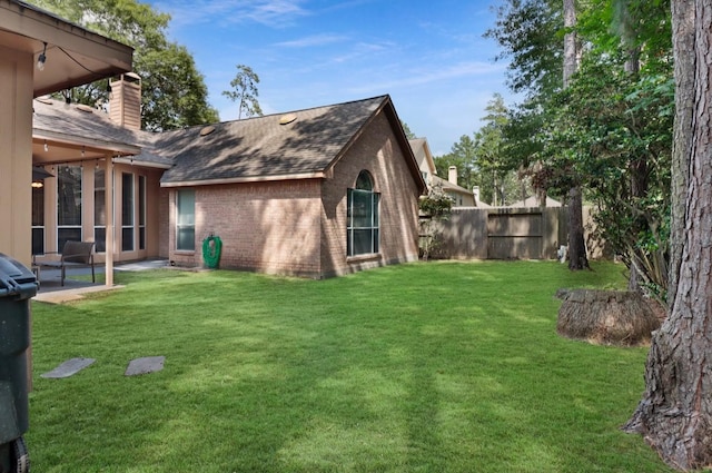 back of house featuring a chimney, roof with shingles, fence, a yard, and brick siding