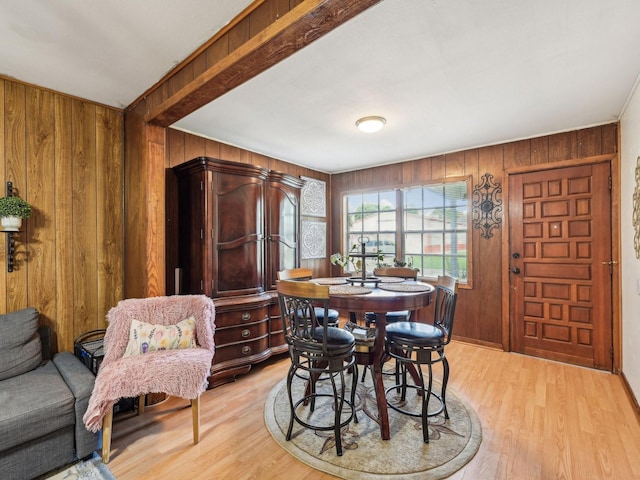 dining area with wooden walls, light wood finished floors, and baseboards